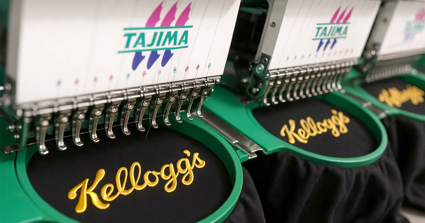 Close-up of Tajima embroidery machines stitching the Kellogg’s logo in golden thread onto black fabric, showcasing high-quality branded embroidery in progress.